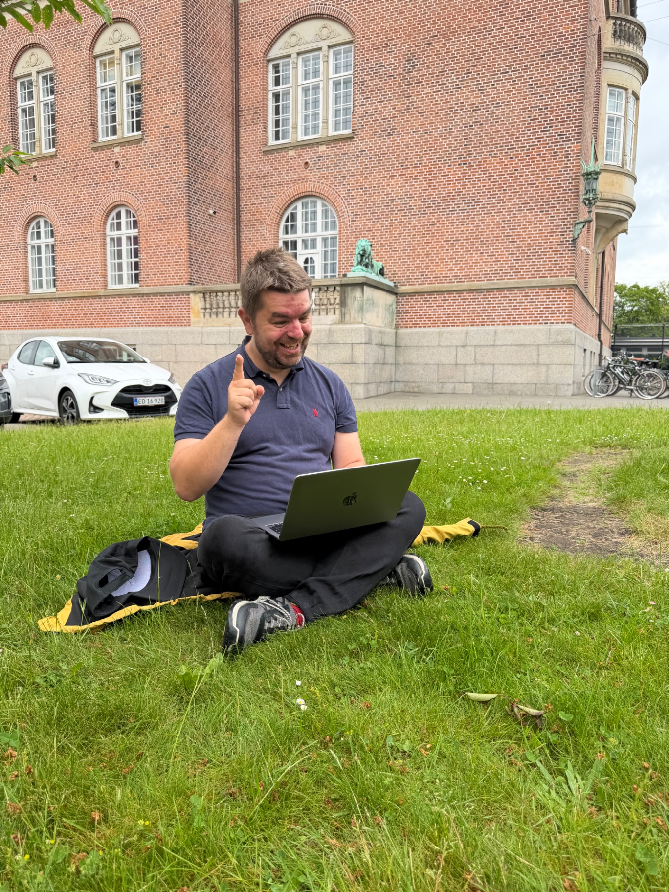Morten Kaj sidder i græsset med sin bærbare computer