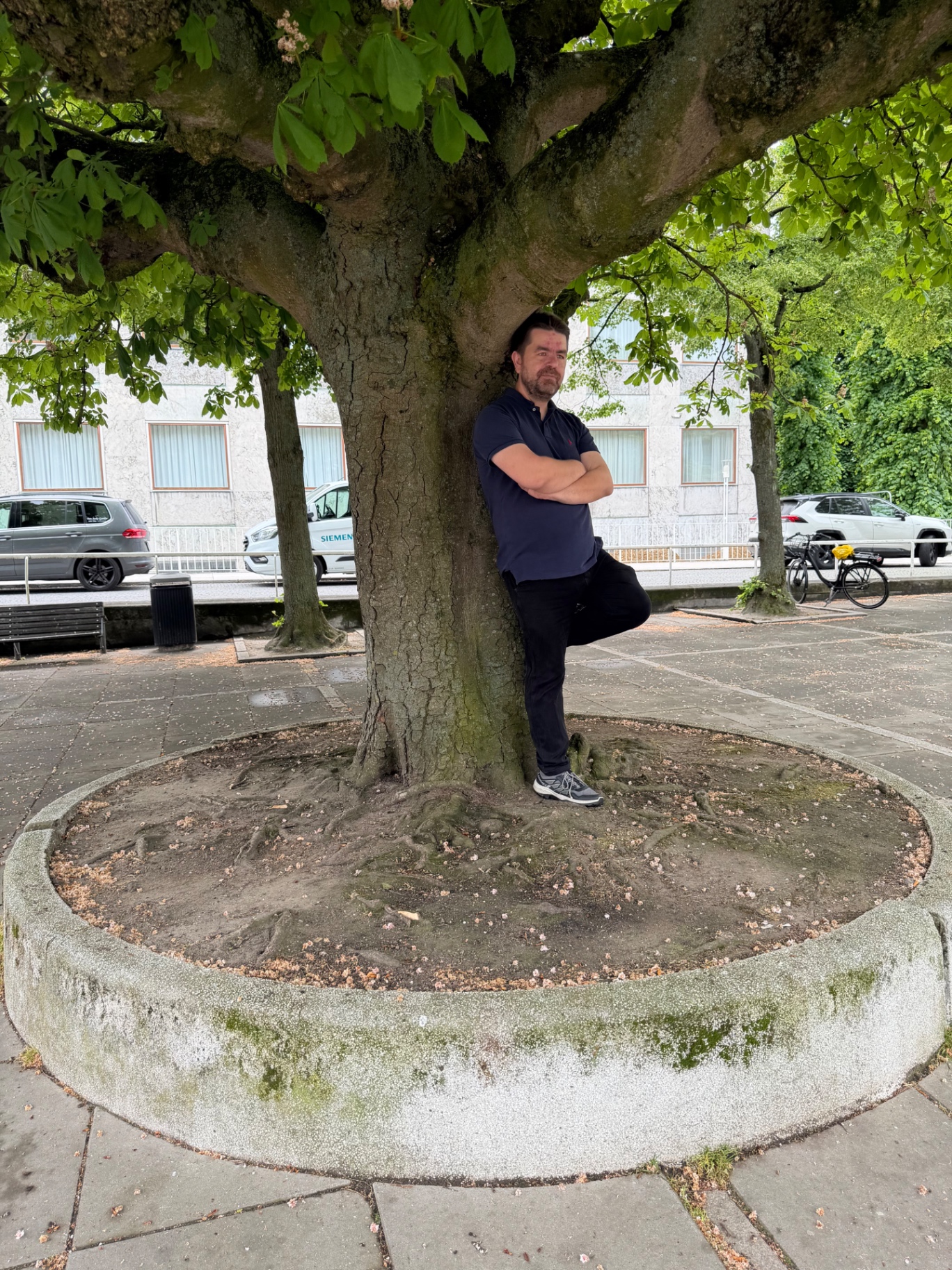 Morten Kaj læner sig op ad et træ på en plads